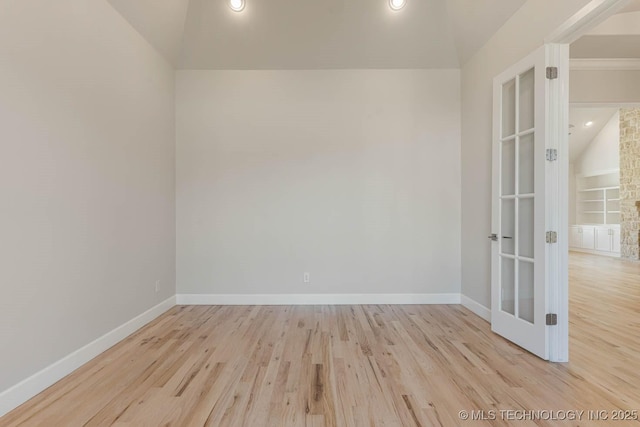 spare room featuring vaulted ceiling, wood finished floors, baseboards, and french doors