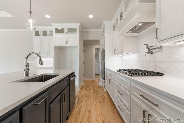 kitchen with white cabinets, recessed lighting, a sink, premium range hood, and appliances with stainless steel finishes