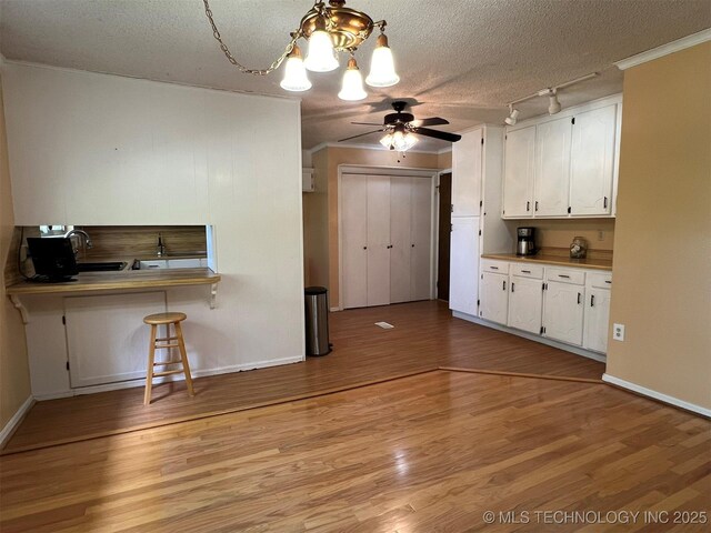 1380 N Lakeview Ave, Mannford, OK 74044 - kitchen with a textured ceiling, light wood-style flooring, ceiling fan with notable chandelier, and white cabinetry