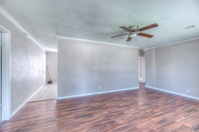 unfurnished room with wood finished floors, a ceiling fan, visible vents, and crown molding