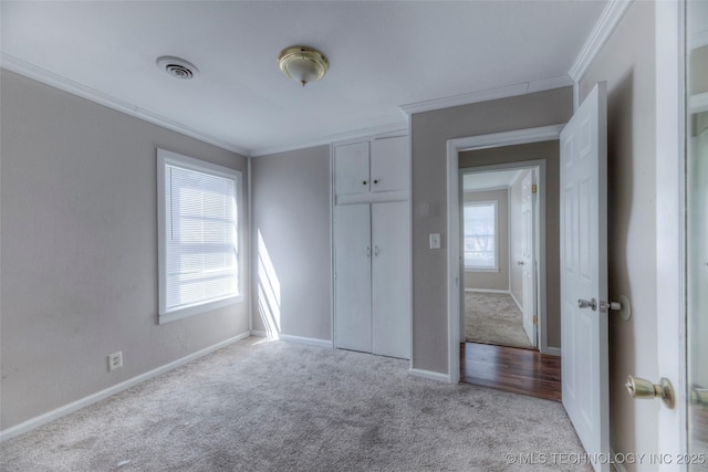 unfurnished bedroom with baseboards, visible vents, carpet, and crown molding