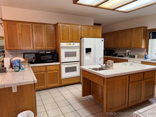 kitchen featuring a sink, decorative backsplash, white appliances, tile counters, and light tile patterned floors