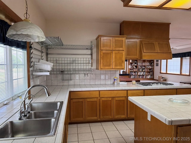 kitchen featuring backsplash, brown cabinetry, white gas cooktop, and a sink