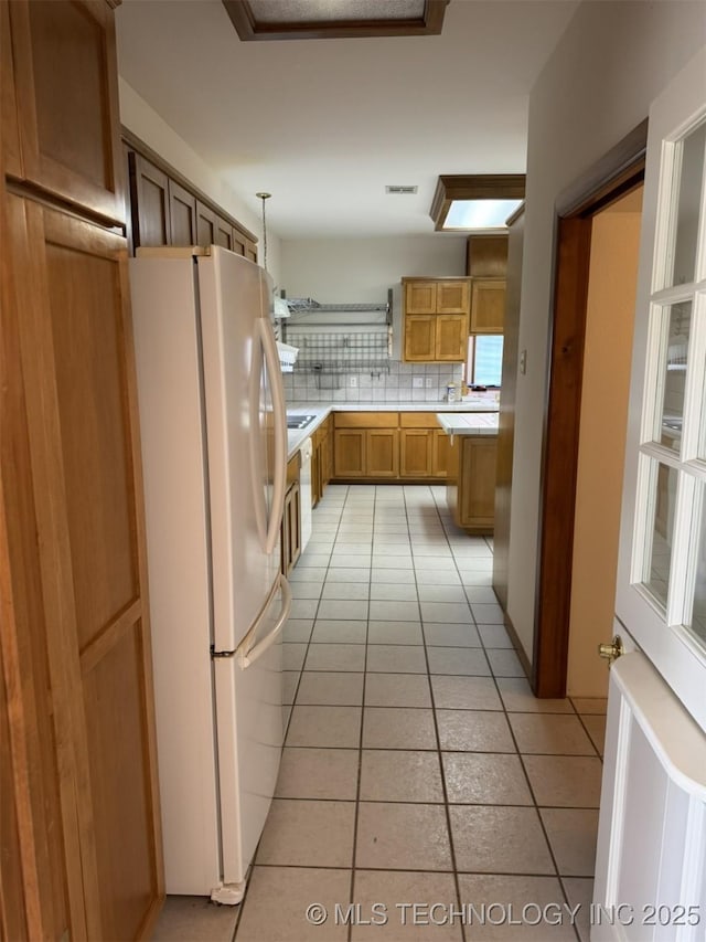 kitchen with open shelves, light tile patterned floors, light countertops, radiator, and freestanding refrigerator