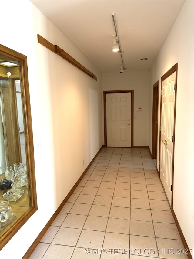 corridor featuring baseboards, track lighting, visible vents, and light tile patterned floors