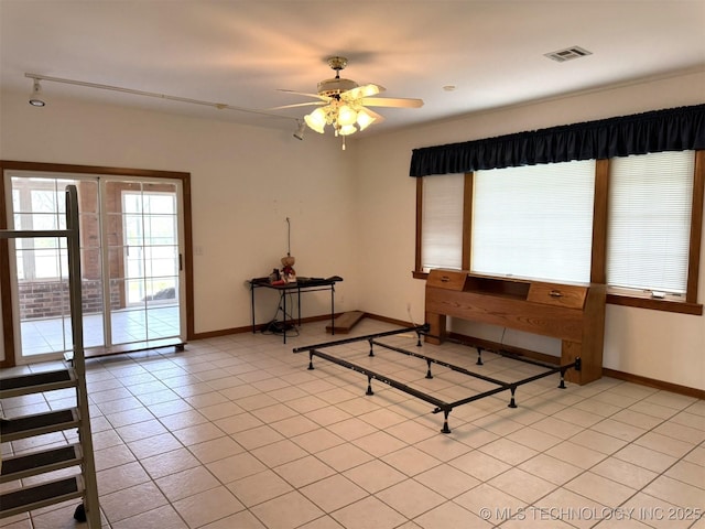 interior space featuring light tile patterned floors, baseboards, visible vents, and ceiling fan