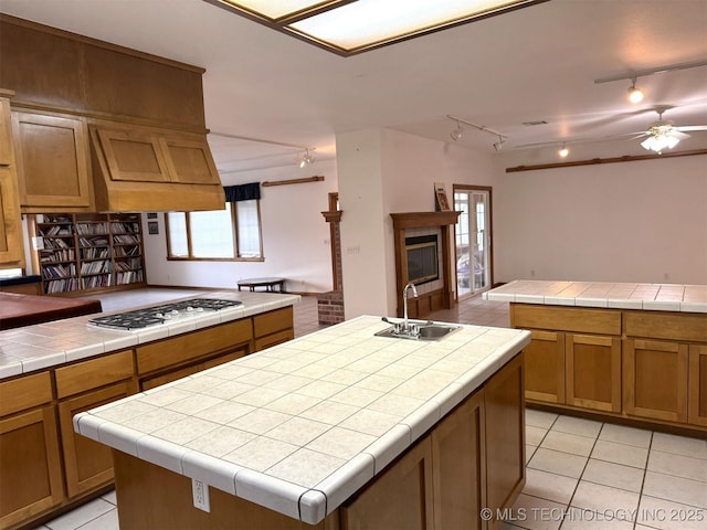 402325 W 2100th Rd, Bartlesville, OK 74006 - kitchen with rail lighting, a sink, white gas stovetop, light tile patterned floors, and a kitchen island