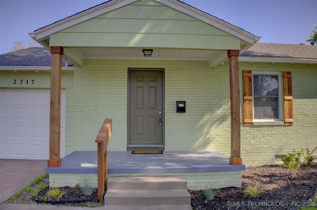 2717 E 3rd St, Tulsa, OK 74104 - entrance to property featuring brick siding, a porch, a garage, and a shingled roof
