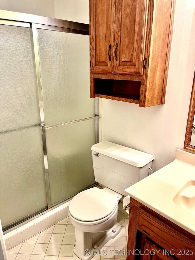 bathroom featuring a shower stall, toilet, vanity, and tile patterned floors