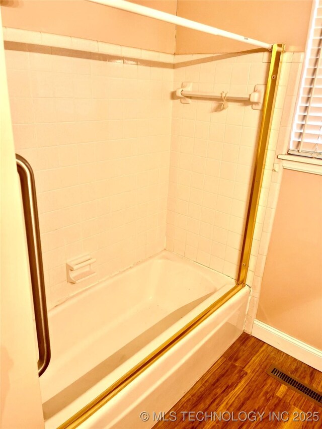 bathroom featuring wood finished floors, visible vents, baseboards, and shower / washtub combination