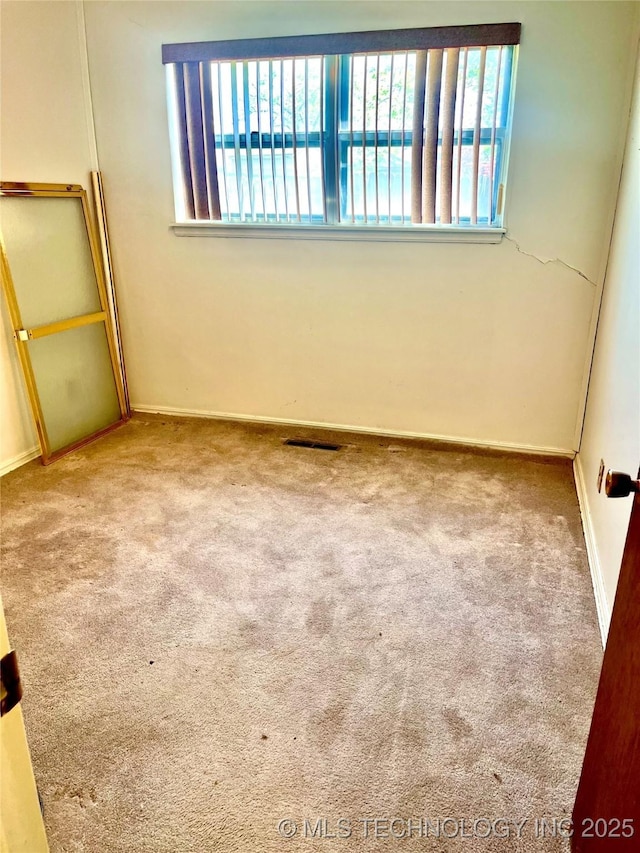 spare room featuring visible vents, carpet flooring, and baseboards