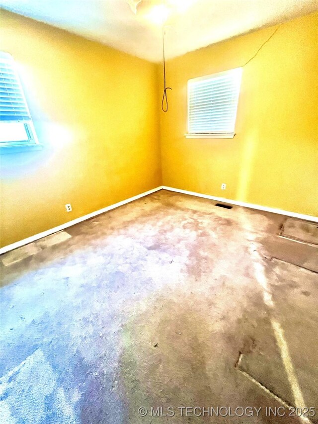 empty room featuring baseboards, visible vents, and a wealth of natural light