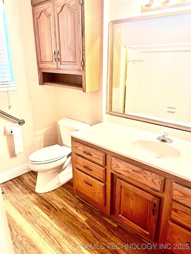 bathroom with toilet, vanity, and wood finished floors
