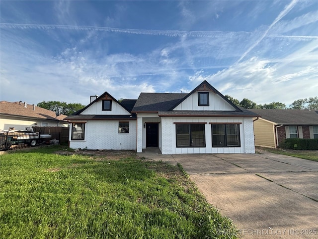 13802 E 19th Pl, Tulsa, OK 74108 - view of front of house featuring a front lawn, driveway, fence, brick siding, and board and batten siding