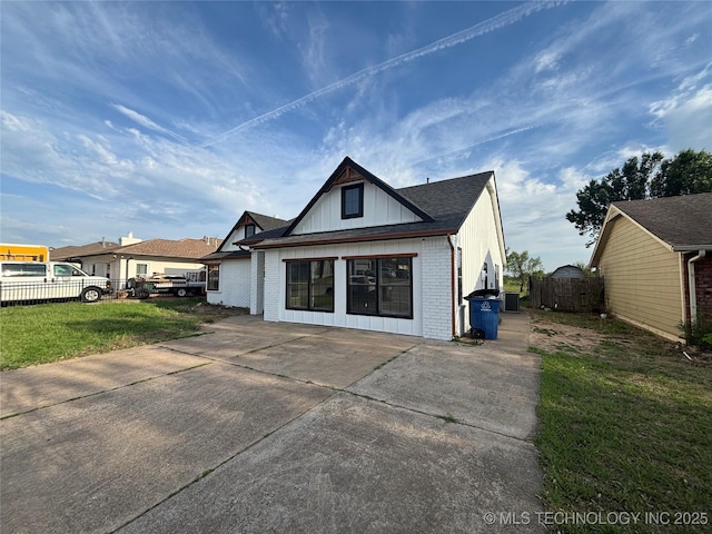 13802 E 19th Pl, Tulsa, OK 74108 - rear view of property featuring fence, a yard, concrete driveway, board and batten siding, and brick siding