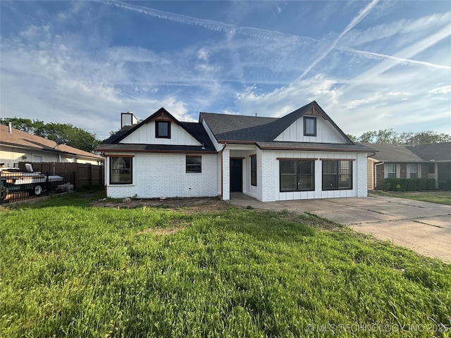 13802 E 19th Pl, Tulsa, OK 74108 - view of front of property featuring fence, brick siding, a front yard, and board and batten siding