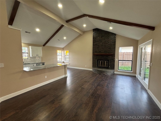 13802 E 19th Pl, Tulsa, OK 74108 - unfurnished living room with visible vents, baseboards, lofted ceiling with beams, a brick fireplace, and dark wood-style flooring