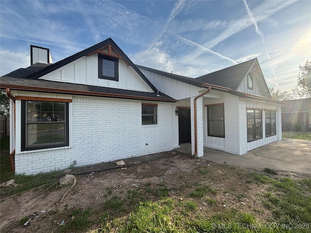 13802 E 19th Pl, Tulsa, OK 74108 - rear view of house featuring brick siding, board and batten siding, and a patio