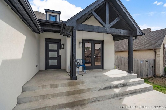 doorway to property with fence, french doors, and stucco siding
