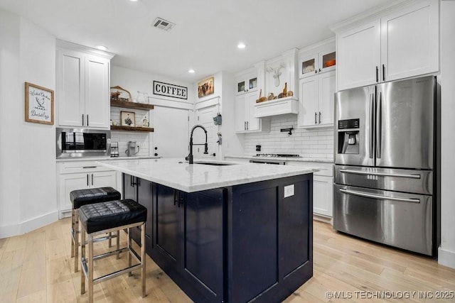 kitchen with open shelves, a sink, light wood-type flooring, appliances with stainless steel finishes, and white cabinetry