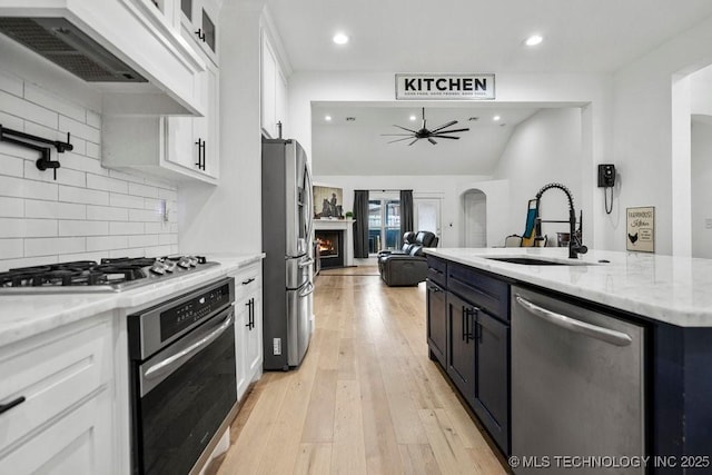 kitchen with a sink, ceiling fan, white cabinetry, premium range hood, and appliances with stainless steel finishes