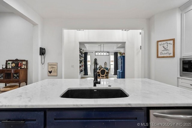 kitchen with black fridge, light stone countertops, blue cabinets, and a sink