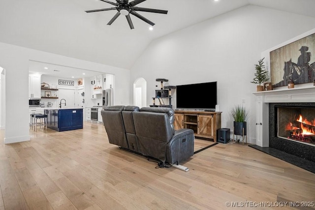 living room featuring recessed lighting, light wood-style floors, a fireplace, high vaulted ceiling, and ceiling fan
