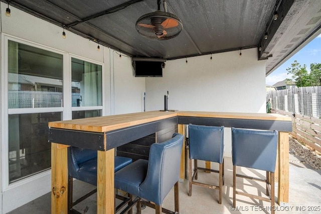 view of patio featuring outdoor dry bar, fence, and a ceiling fan