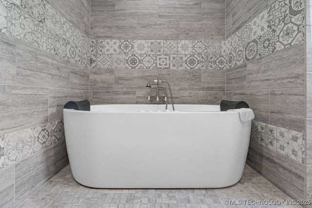bathroom featuring tile walls and a freestanding bath
