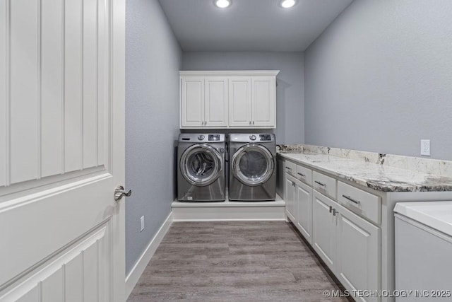 clothes washing area featuring recessed lighting, light wood finished floors, washing machine and dryer, baseboards, and cabinet space