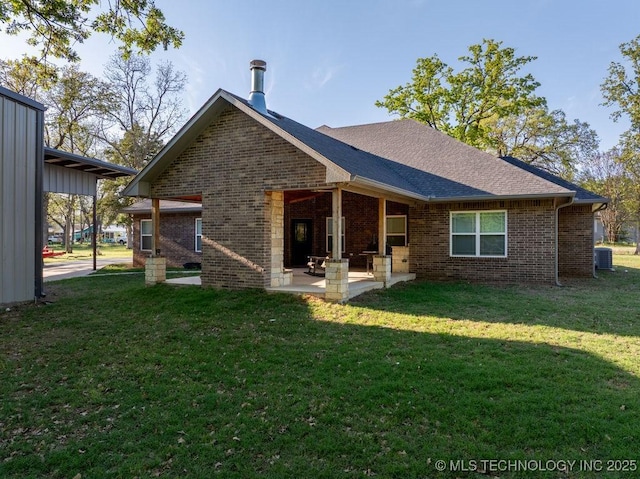 back of property with a yard, brick siding, a patio area, and cooling unit
