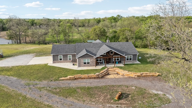 craftsman-style house with a front lawn, driveway, covered porch, and stone siding