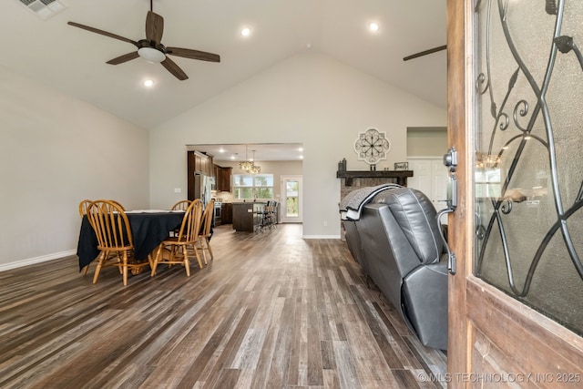 living area with visible vents, a brick fireplace, baseboards, dark wood-type flooring, and ceiling fan with notable chandelier