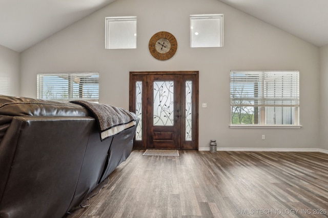 foyer with baseboards, wood finished floors, and high vaulted ceiling