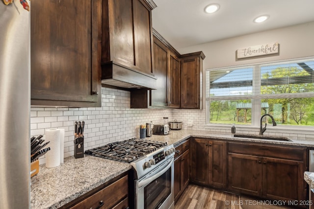 kitchen with light stone counters, a sink, a wealth of natural light, and stainless steel gas range