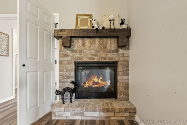 interior details featuring a brick fireplace, baseboards, and wood finished floors