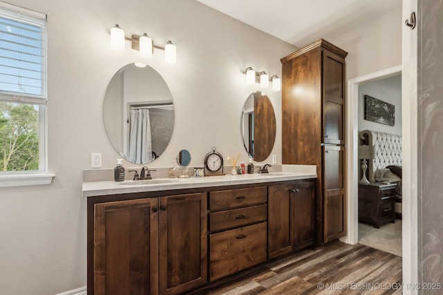 full bathroom with double vanity, a sink, and wood finished floors