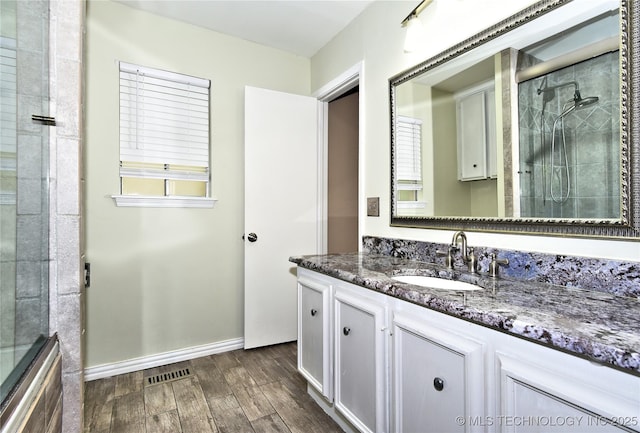 3638 E 69th Pl, Tulsa, OK 74136 - bathroom featuring a tile shower, visible vents, baseboards, wood finished floors, and vanity