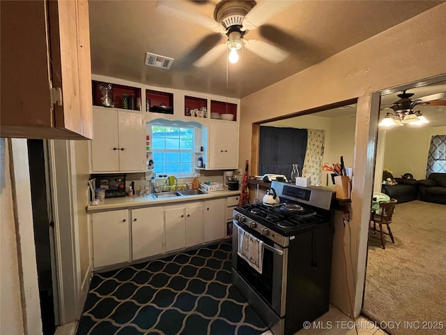 kitchen featuring dark carpet, stainless steel range with gas stovetop, ceiling fan, and a sink