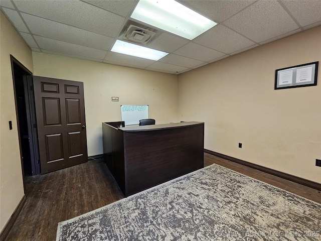 office space featuring baseboards, a paneled ceiling, visible vents, and dark wood-style floors