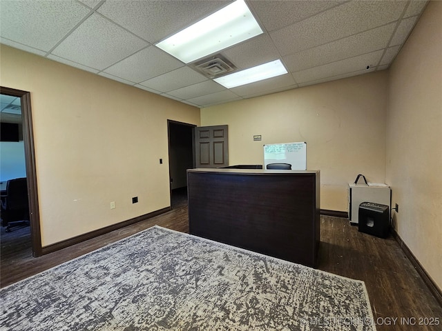 home office with visible vents, a drop ceiling, and dark wood finished floors