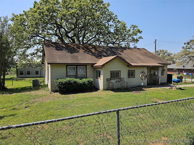 view of front of property with a fenced backyard, roof with shingles, a front yard, and central AC unit