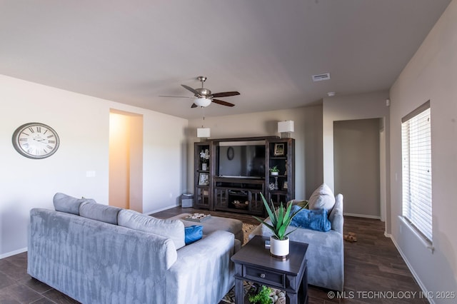 living area featuring baseboards, a ceiling fan, visible vents, and dark wood finished floors