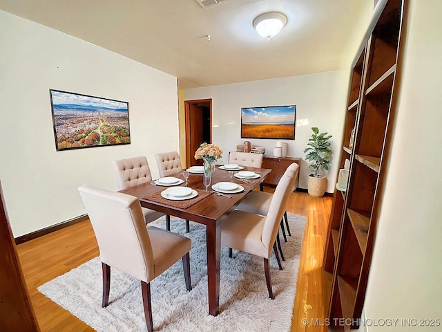 dining area featuring light wood-type flooring, visible vents, and baseboards