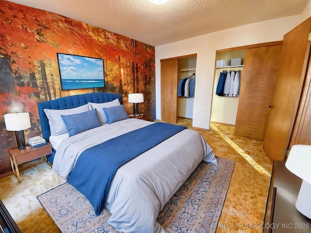 bedroom featuring multiple closets, a textured ceiling, and carpet floors