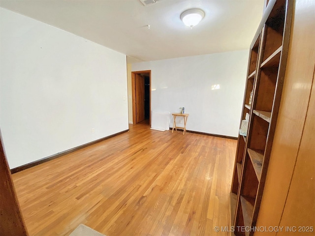 empty room featuring light wood finished floors, baseboards, and visible vents