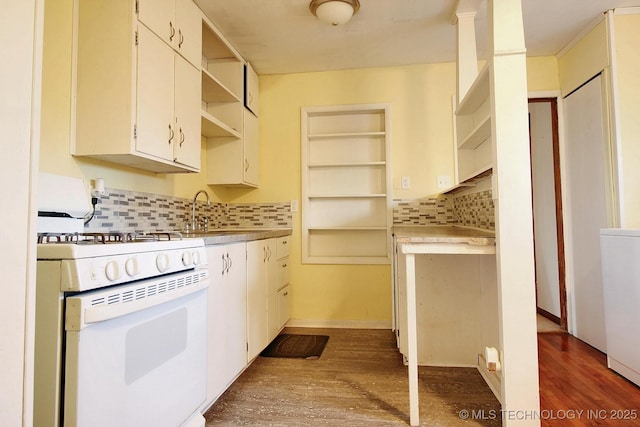 kitchen with open shelves, white range with gas stovetop, decorative backsplash, and a sink