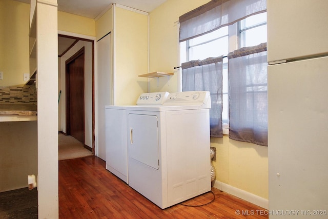 clothes washing area featuring baseboards, wood finished floors, washer and clothes dryer, and laundry area