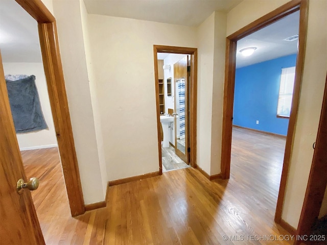 hall with wood finished floors, baseboards, and a sink