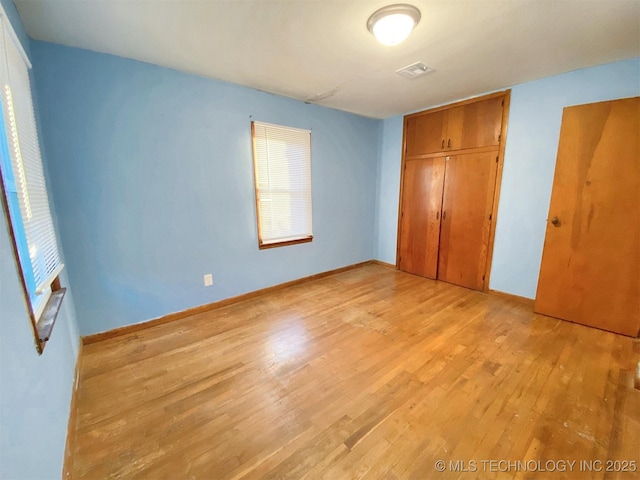 unfurnished bedroom with baseboards, a closet, visible vents, and light wood-type flooring